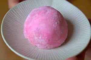 Round pink ball of mochi with faintest bit of brown brownie shwoing through skin.