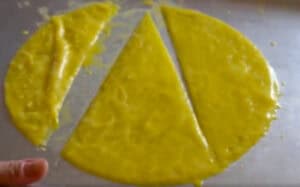 Three-layered rice paper dipped in egg batter, cut into two semi-circles and one triangle on parchment paper.