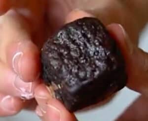 Fingers shaping brownie into a ball for wrapping with mochi.