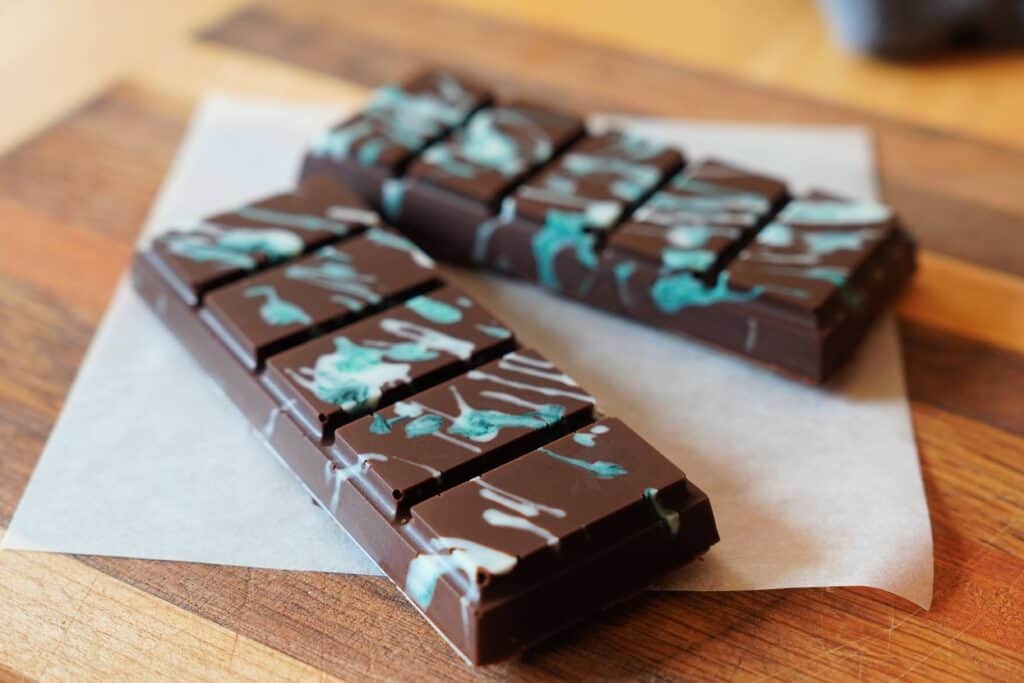 Two, five-sectioned chocolate bars with white/blue splatter pattern on top.